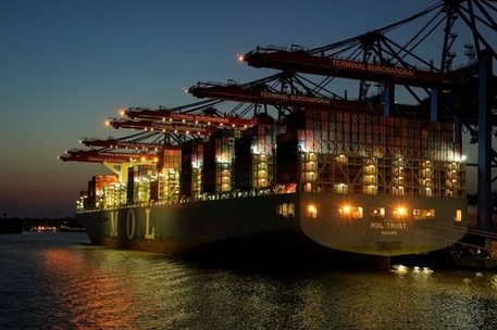 Das Bild zeigt ein Containerschiff im Hafen bei Nacht.