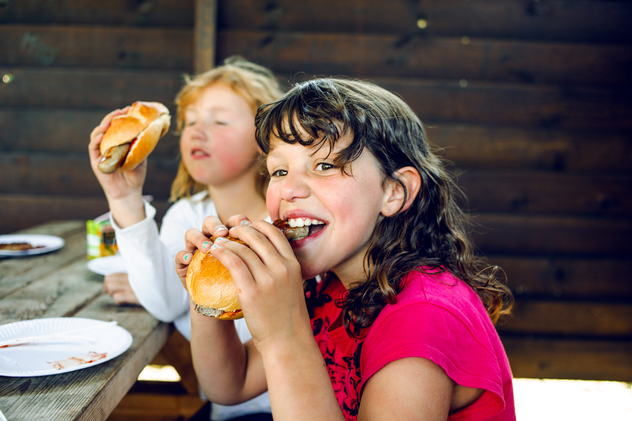 Mädchen essen Bratwurst im Brötchen